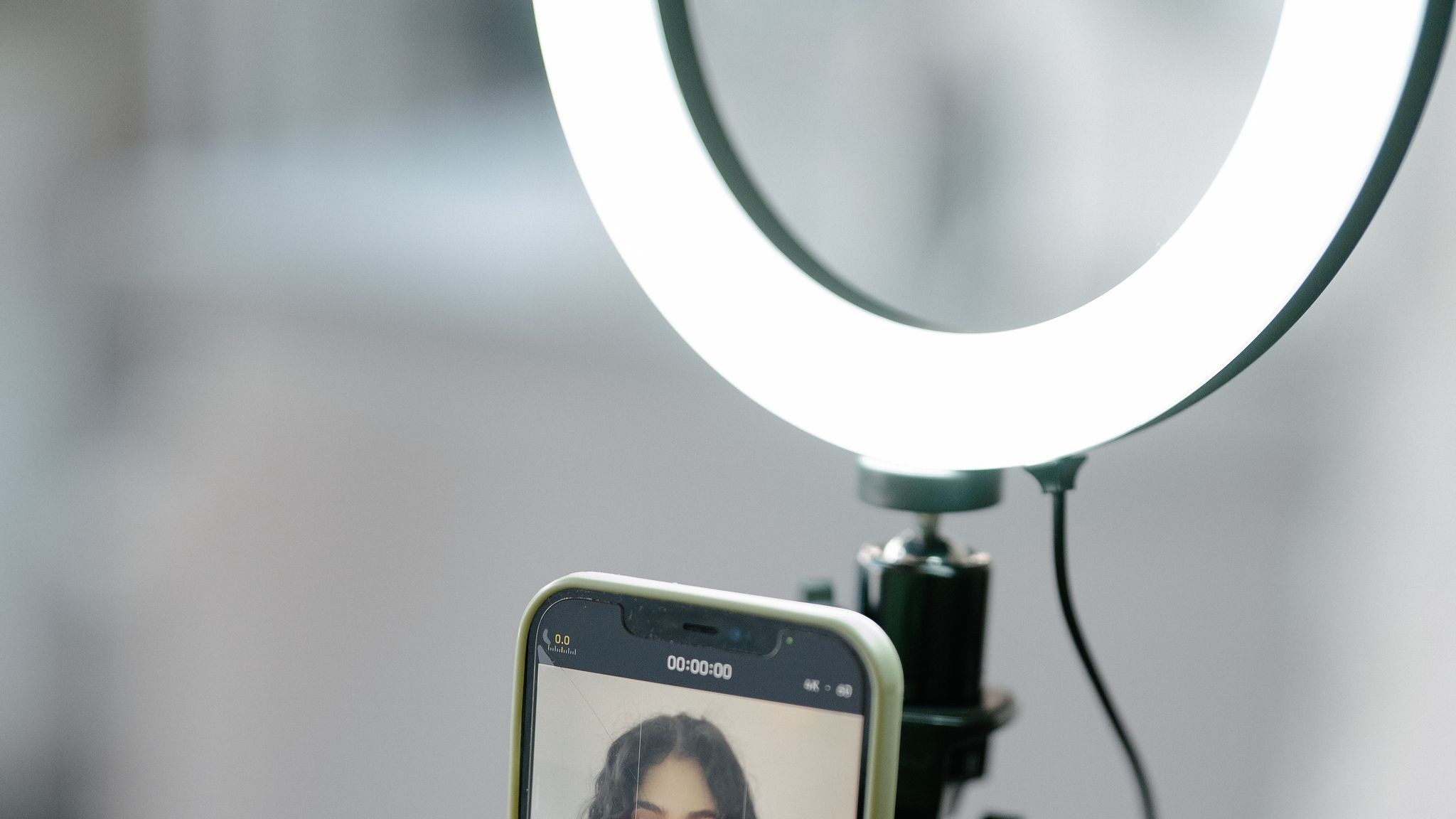 Woman filming a vlog with a smartphone and ring light indoors
