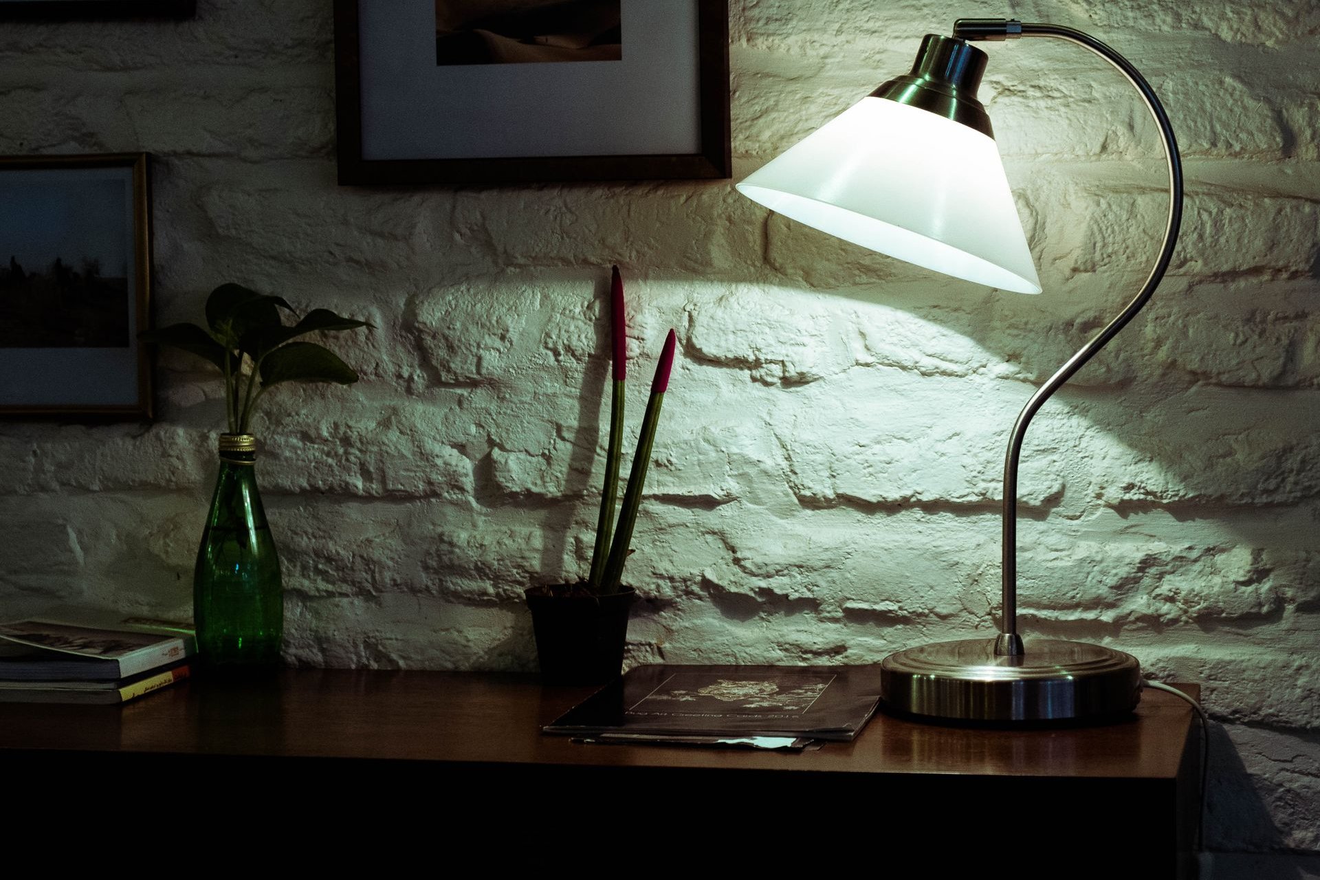 Gooseneck desk lamp glowing warmly on a home office desk at night